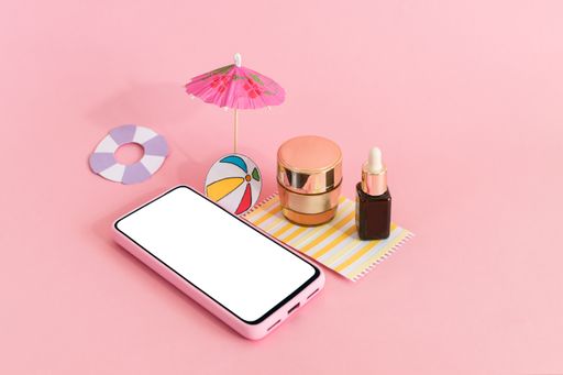 The skincare cream containers with a beach umbrella and a smartphone on pink background
