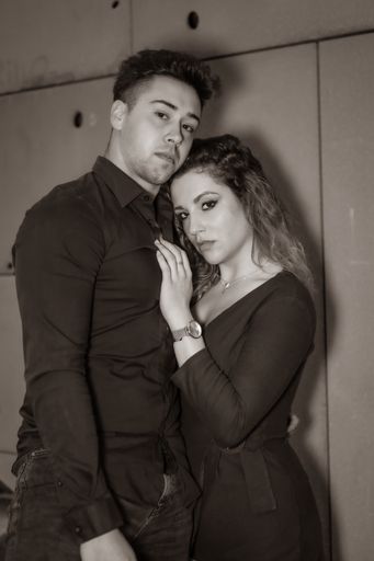 A grayscale shot of a loving fashionable couple hugging and posing
