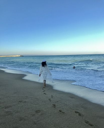 A rear view of a woman with footprints on the beach
