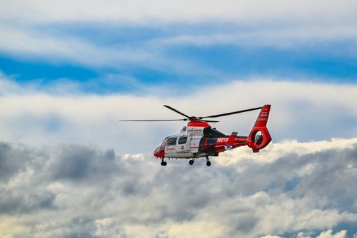 A view of a rescue helicopter taking off, under a cloudy sky.