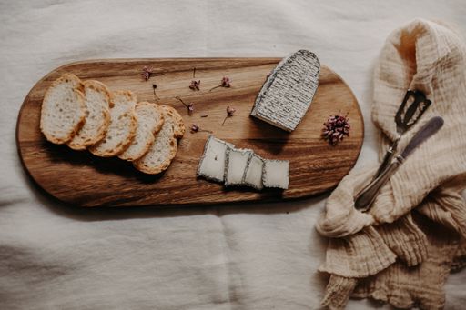 A high angle shot of delicious cheese and slices of bread on a wooden board