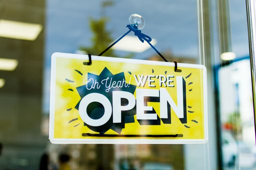 A selective focus of signage with a text We're Open through the glass door against a blurred background