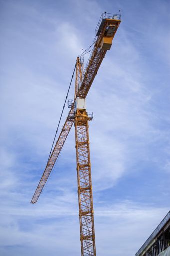 A low angle shot of a crane against the blue cloudy sky
