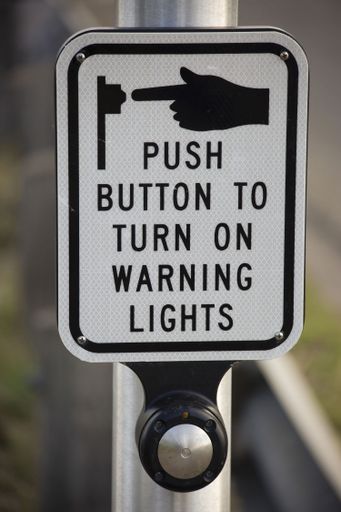 A sign saying 'push button to turn on warning lights'