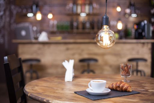 An elevated view of a wooden table with a steaming cup of coffee, a croissants, and assorted pastries arranged to create an inviting breakfast display