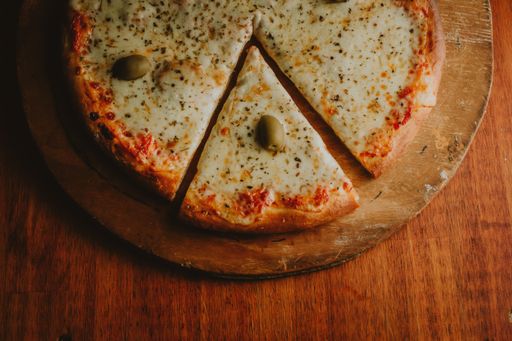 A top view of delicious and appetizing cheese and olive pizza on a wooden board