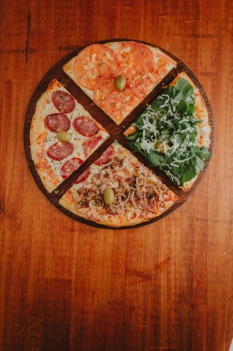 A top view of delicious and appetizing assorted pizzas on a wooden table
