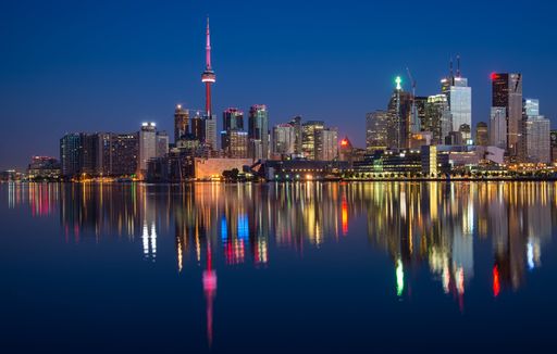 A stunning aerial view of Toronto at night featuring the city skyline illuminated by the ambient light from across the lake