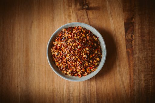 A top view of dried chili flakes in a bowl on a wooden table