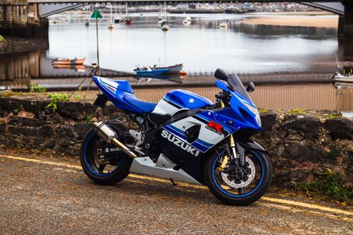 A close-up of a Suzuki motorcycle parked against a backdrop of mountains in Conwy, Wales
