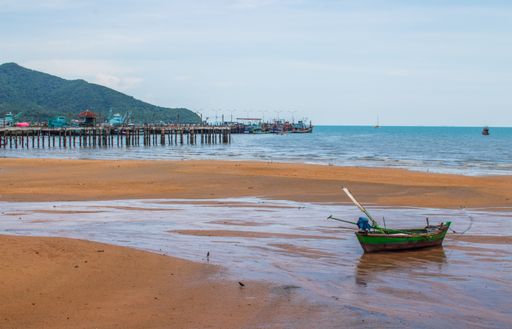 A small fishing boat on a sandy beach of the Gulf of Thailand