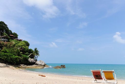A closeup shot of chairs on the sandy seashore on the beach - vacation concept
