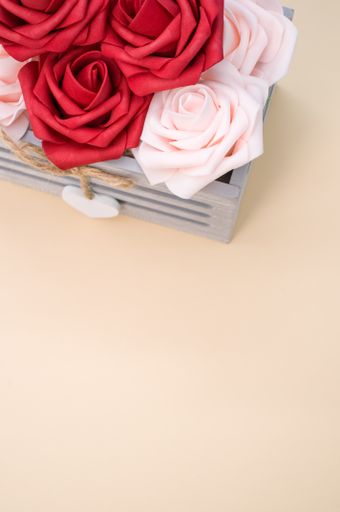 A vertical shot of beautiful red and white roses in a box isolated on a beige background