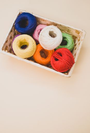 A vertical shot of colorful thread rolls in a box isolated on a beige background