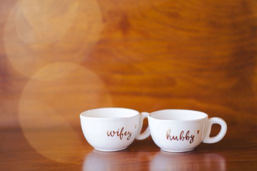 A pair of porcelain mugs arranged on top of a wooden table against Christmas bokeh lights