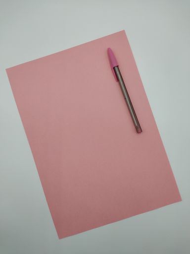 An overhead shot of a pink pen on a corresponding pink paper