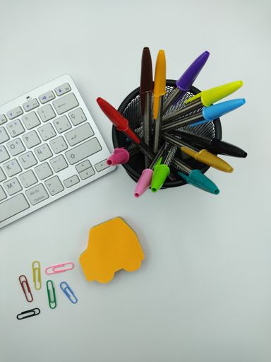 An overhead shot of an office desk with colorful pens and a keyboard
