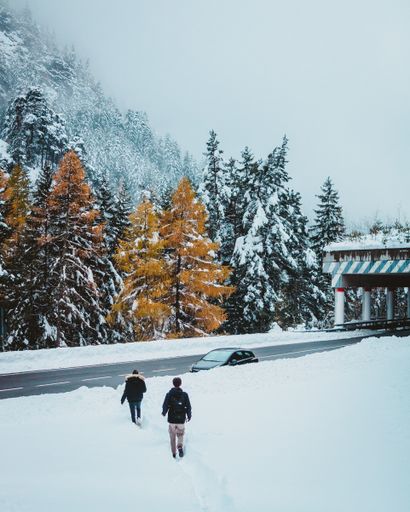 A couple walking in the snow next to the highway