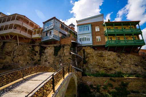A scenic view of a bridge with beautiful houses on a cliff background