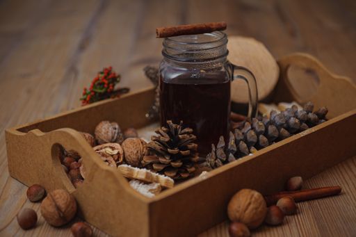 A closeup shot of a juice in a glass jar and surrounded by Christmas cone decorations