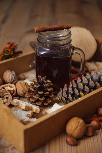 A vertical shot of a juice in a glass jar and surrounded by Christmas cone decorations