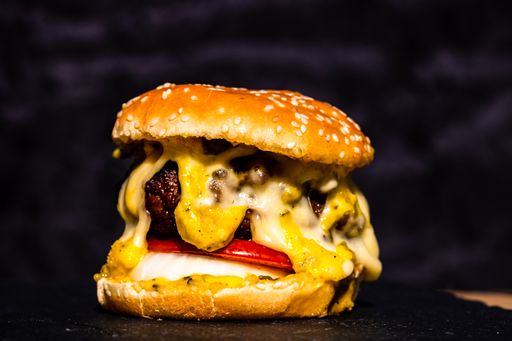 A closeup shot of a tasty beef cheeseburger with melted cheese isolated on black background