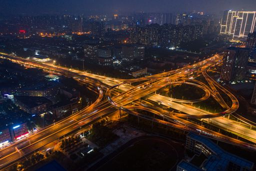 An aerial view of an intersection illuminated by orange-yellow street lights at night.