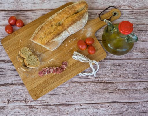A top view of a classic Catalan dish, Pan con Tomate, with garlic, olive oil and tomatoes on a wooden cutting board
