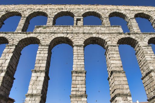A low angle shot of the Aqueduct of Segovia under the sunlight and a blue sky in Spain