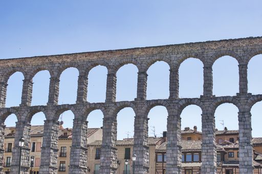 The Aqueduct of Segovia surrounded by buildings under the sunlight in Spain