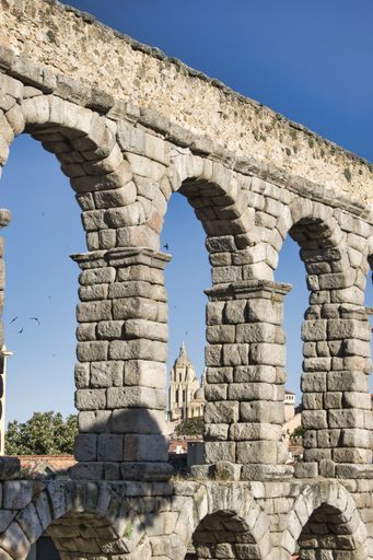 A vertical shot of the Aqueduct of Segovia under the sunlight and a blue sky in Spain