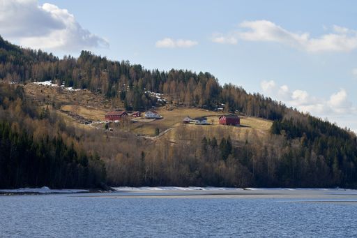 A beautiful view of houses on a tree-covered hill behind a calm lake
