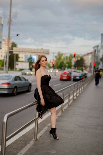 A vertical shot of a white Caucasian woman wearing a classy black dress and posing for a picture