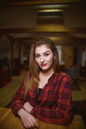 A young woman in a red shirt and lipstick smiling and looking at the camera