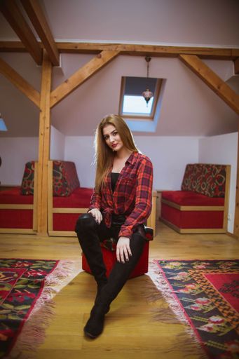 A young lady with blonde hair wearing a red shirt and posing on the chair