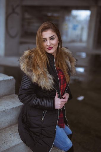 A shallow focus vertical shot of a young woman leaning on the stairs