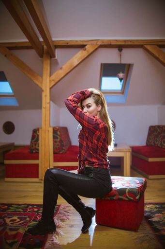 A young Caucasian female with brown hair wearing a black shirt sitting on a chair