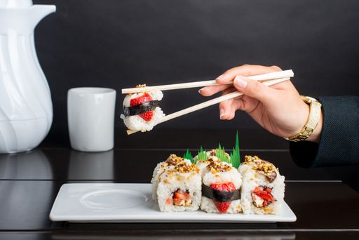 A person using chopsticks to eat dessert sushi rolls