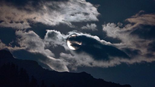 The full moon behind the dark clouds at night captures in Manali, Himachal Pradesh
