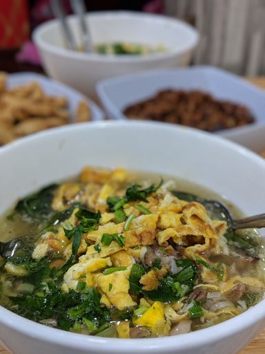 A vertical shot of a delicious soup with other dishes in the background