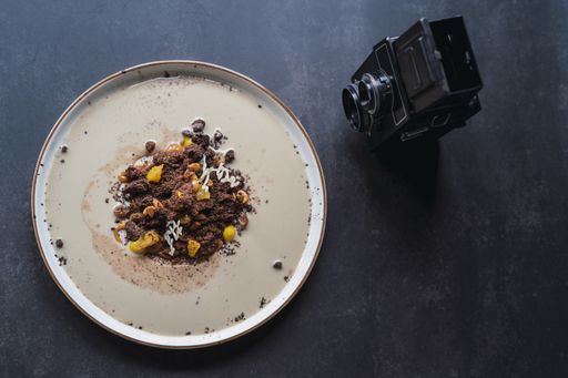 A top vi of chocolate biscuit crumbles with fruits and sweet sauce on a plate on the table