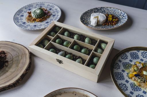 A closeup of small cookies in a wooden box on the table with delicious decorated desserts on it