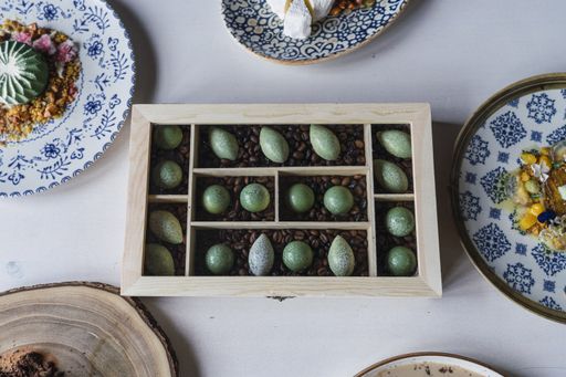 A high angle shot of small cookies in a wooden box on the table with delicious decorated desserts on it