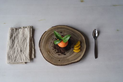 A top view of a mandarin shaped pastry on cookie crumbs on a board on the table