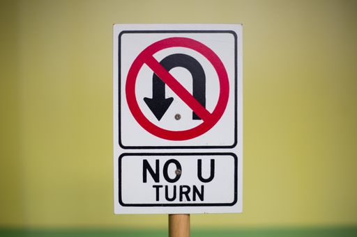 A closeup shot of a white "No U-turn" sign on a blurred background