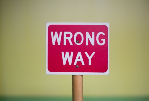 A closeup shot of a red "Wrong Way" sign on a blurred background
