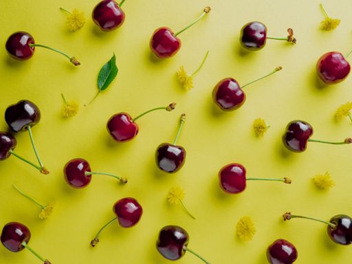 A top view of fresh juicy cherries and flowers isolated on a yellow background