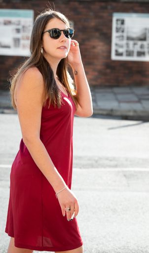 A vertical of woman in a red dress walking down the street
