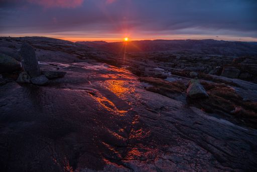 A closeup shot of the sunrise over a landscape of rocky hills