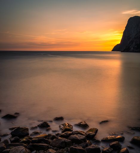 A picturesque view of a vibrant sunset on the beach with large rocky formations in Lofoten, Norway